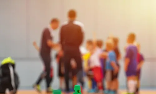 Grupa dzieci uważnie słuchająca wskazówek trenera podczas zajęć Sportuś