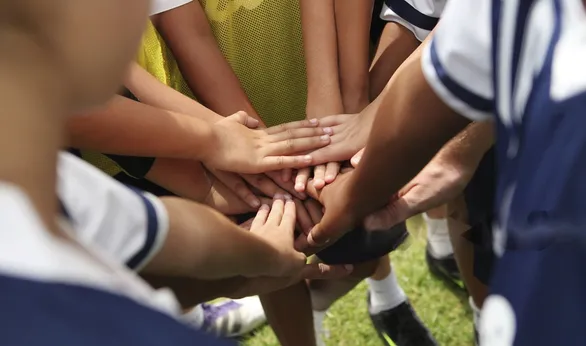 team gathered in a circle and each team member put a hand in the middle of the circle before game in order to cheer the team up